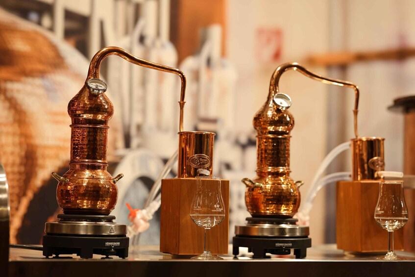 Three copper stills with glassware on a countertop. 5