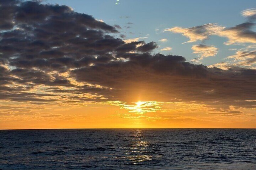 A sunset over the ocean with clouds and a visible sun reflection on the water. 4
