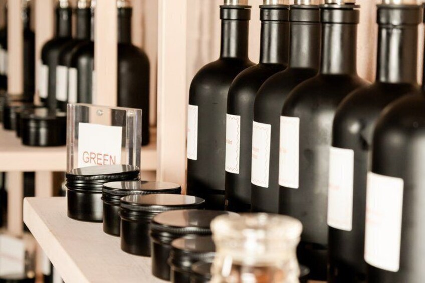 A row of wine bottles with labels and a glass container labeled 'GREEN' in a store. 1
