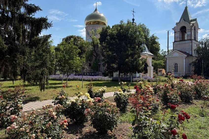 A church with a golden dome, a bell tower, and a garden with roses. 5