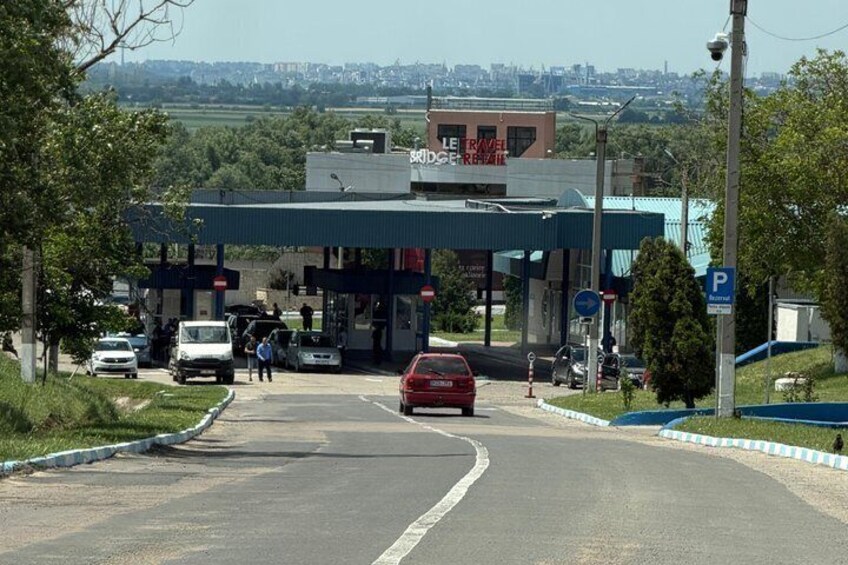 A gas station with multiple fuel pumps, a red car approaching, and a clear sky. 2