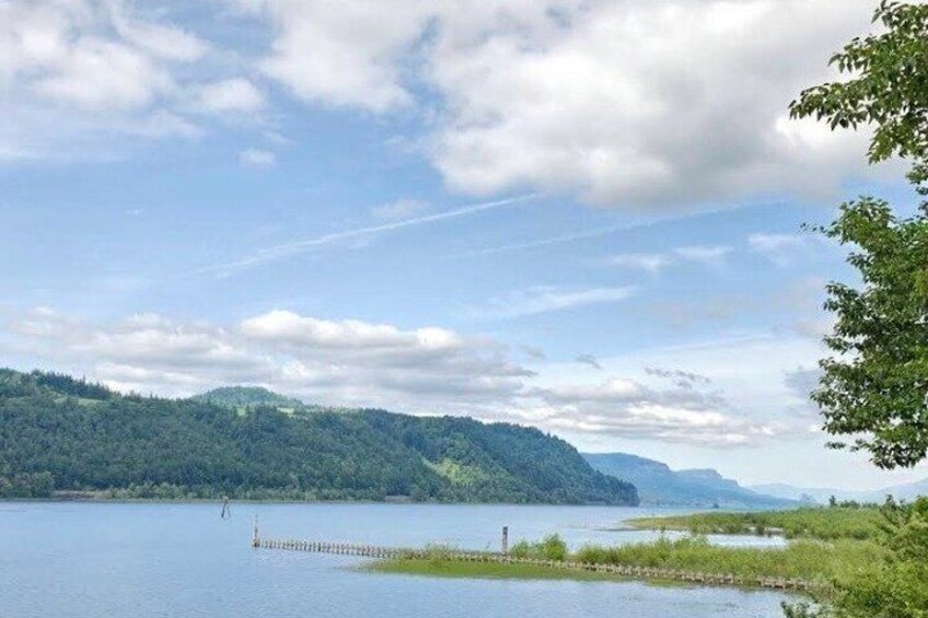 A calm lake surrounded by hills, a clear sky, and a distant shoreline. 4
