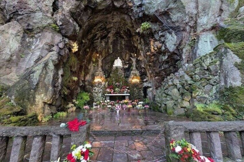 A cave interior with a statue, altar, and flowers. 3