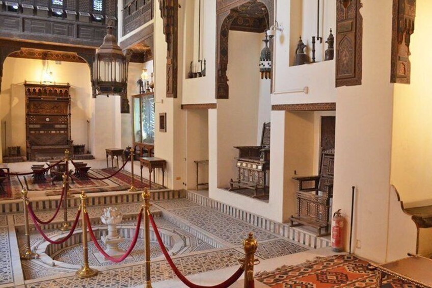 A grand hall with ornate furniture, a fountain, and intricate tile work. 3