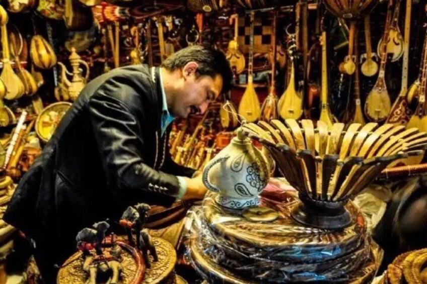 A person examining a traditional stringed instrument with a decorative case. 3