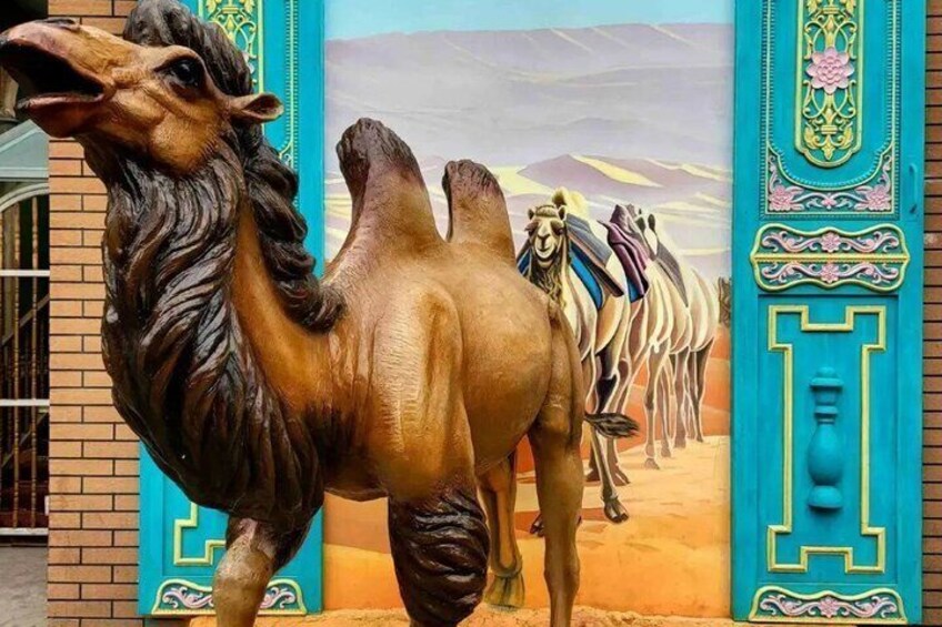 A camel sculpture with a desert mural in the background. 1