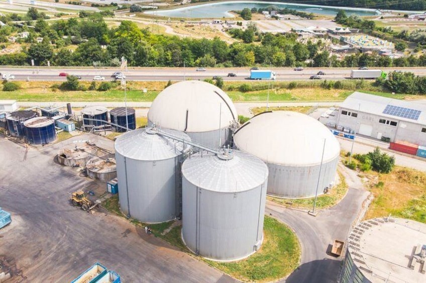 Large industrial storage tanks, a road, and a building with solar panels. 1