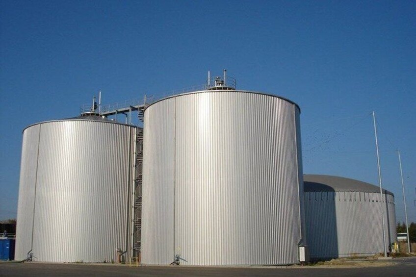 Two large cylindrical storage tanks with a ladder leading to the top, set against a clear blue sky. 2