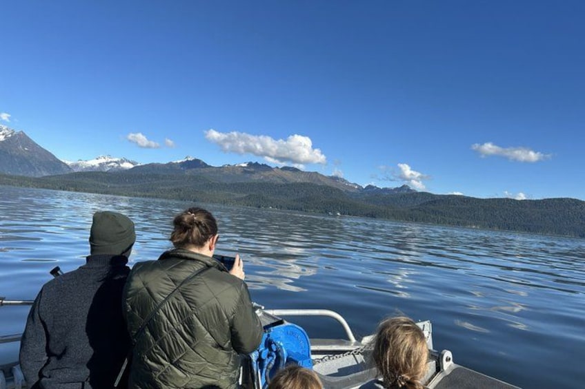 A group of people on a boat, a calm lake, and mountains in the background. 4