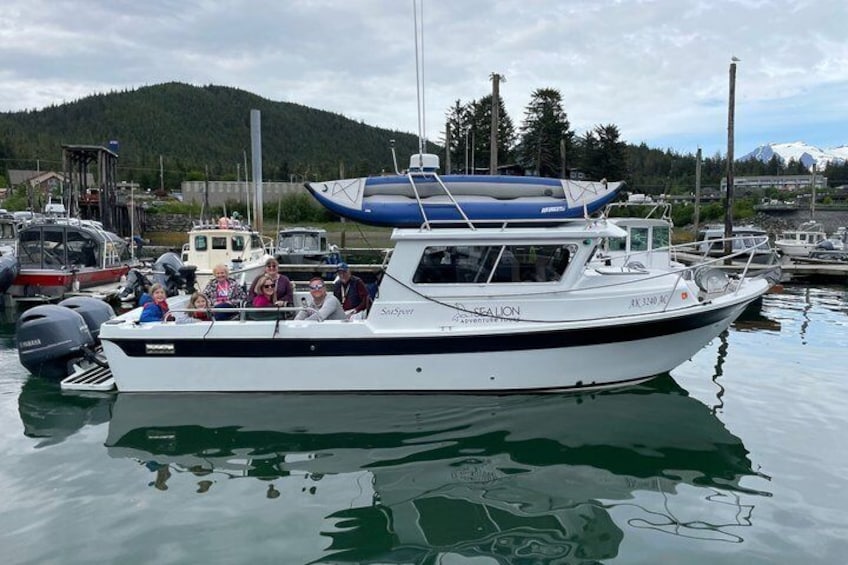 A white boat named 'SEALION' docked at a marina with a mountainous backdrop. 1