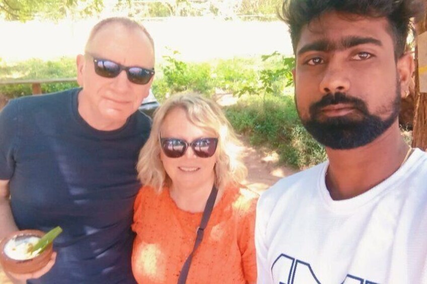 Three people outdoors, one holding a drink. 1