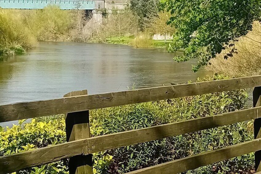 A wooden bridge over a calm river with greenery on the banks. 4
