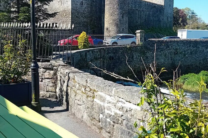 A stone wall with a metal fence, a red car, and a white car parked behind it. 4