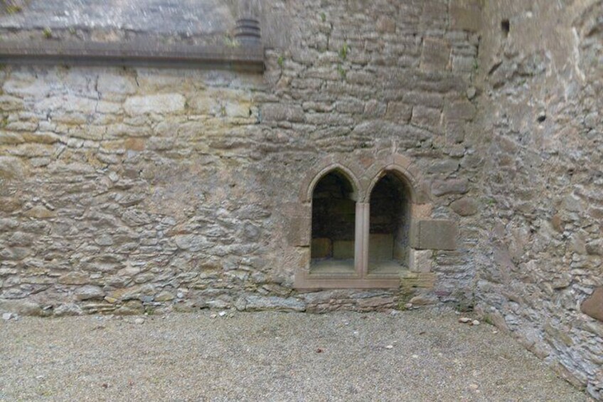 A stone wall with a small arched window. 2