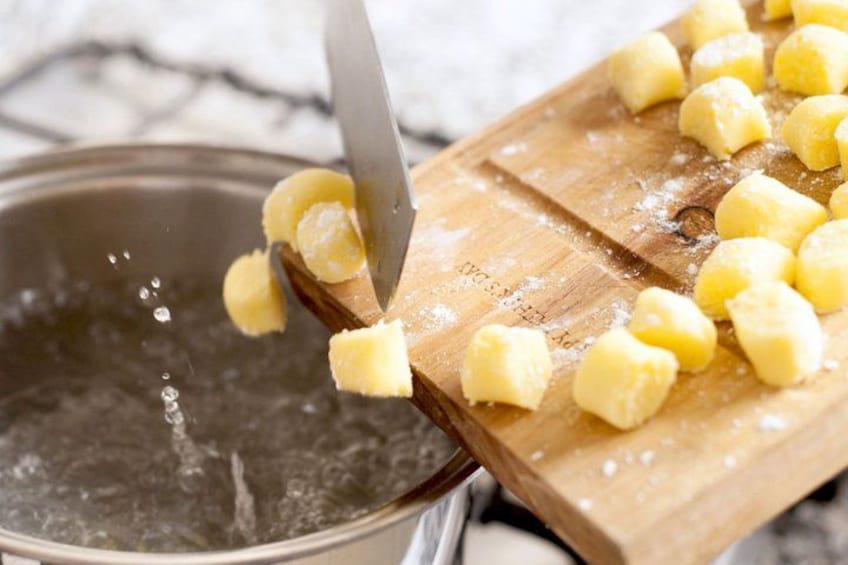 A cutting board with pieces of dough and a knife. 2