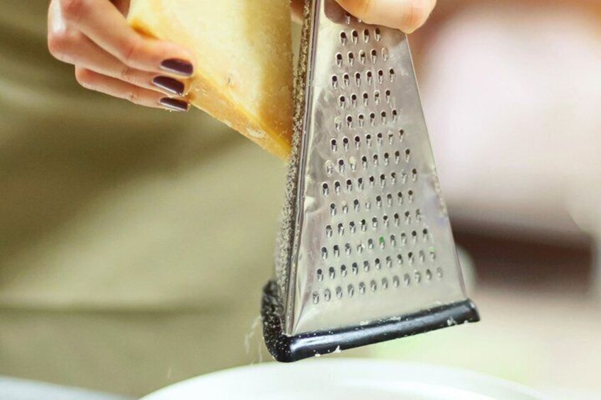 A person grating cheese on a metal grater. 3