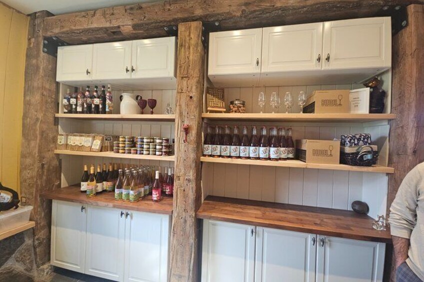 A kitchen with wooden beams, white cabinets, and shelves stocked with bottles and jars. 1