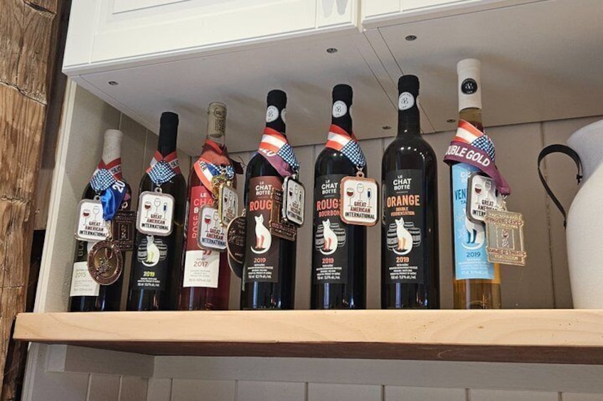 A shelf with bottles of wine, each with a medal and ribbon indicating awards. 3