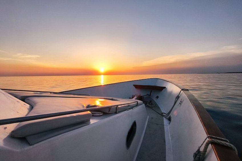 A boat at sunset with calm water and a clear sky. 3