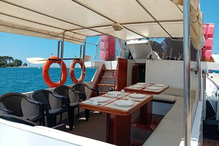 A boat's dining area with tables, chairs, life rings, and a covered section. 3