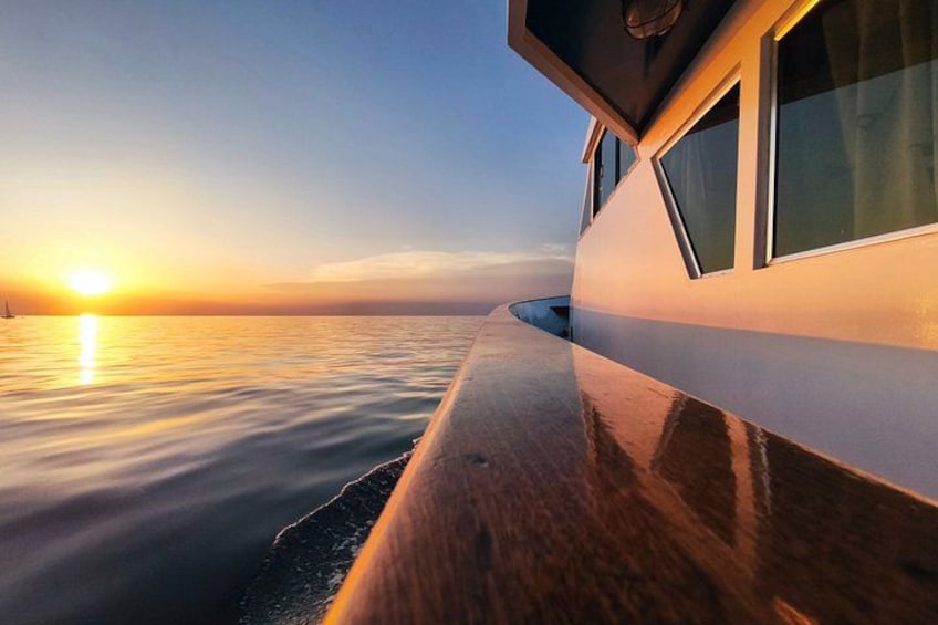 A boat at sunset with calm water and a clear sky. 2