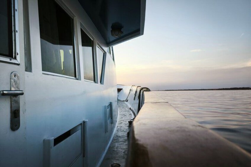 A boat with a metal railing, a window, and a view of the water. 2