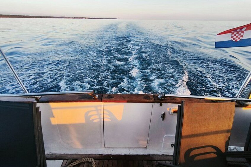 A boat's wake in the ocean, a Croatian flag, and a wooden deck. 3