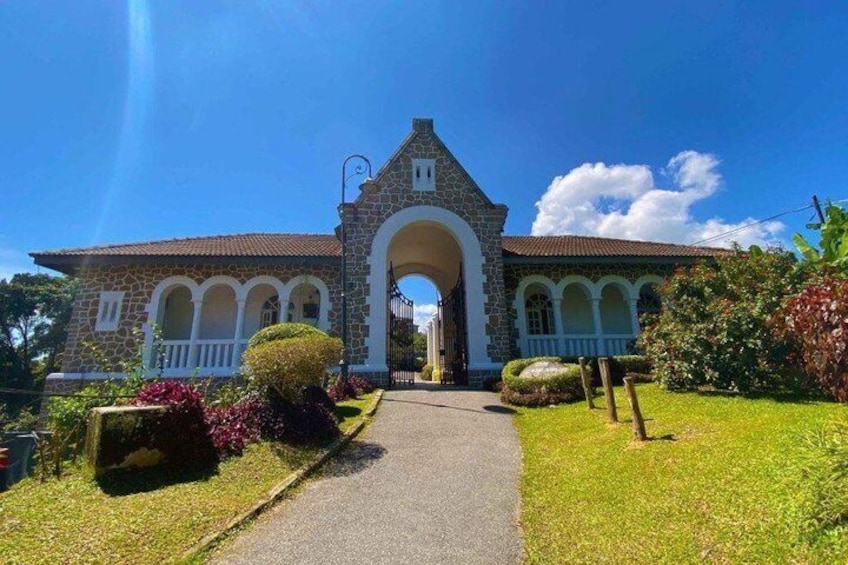 A historic building with a central archway, surrounded by well-maintained gardens and a clear sky. 5
