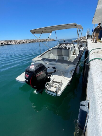 A small motorboat docked at a pier with a clear blue sky and calm water. 3