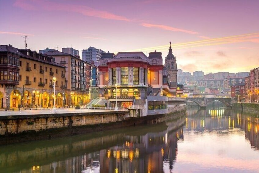 A riverside cityscape with illuminated buildings and a bridge. 1