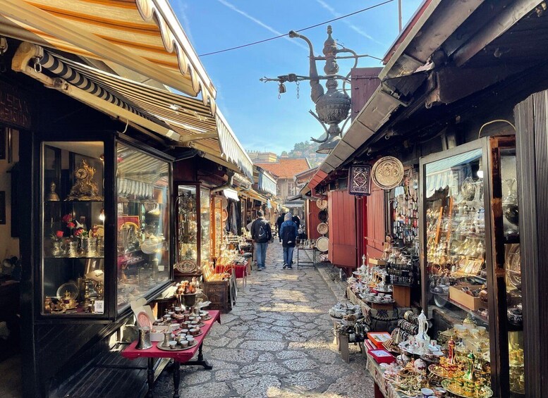 A narrow street with shops on either side selling various items. 1