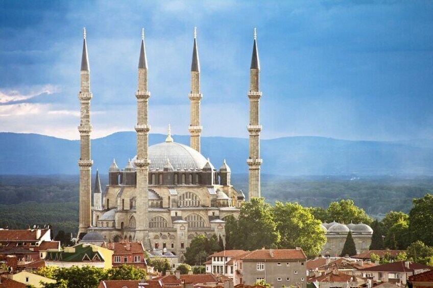 A historic mosque with four minarets and a large dome, surrounded by a town with red-roofed buildings. 3