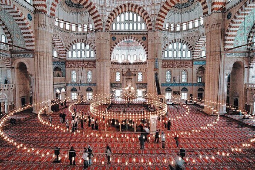 A large mosque with red carpets, arches, and a central courtyard. 4
