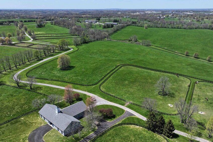 A large green field with a winding path, a barn, and a few trees. 2