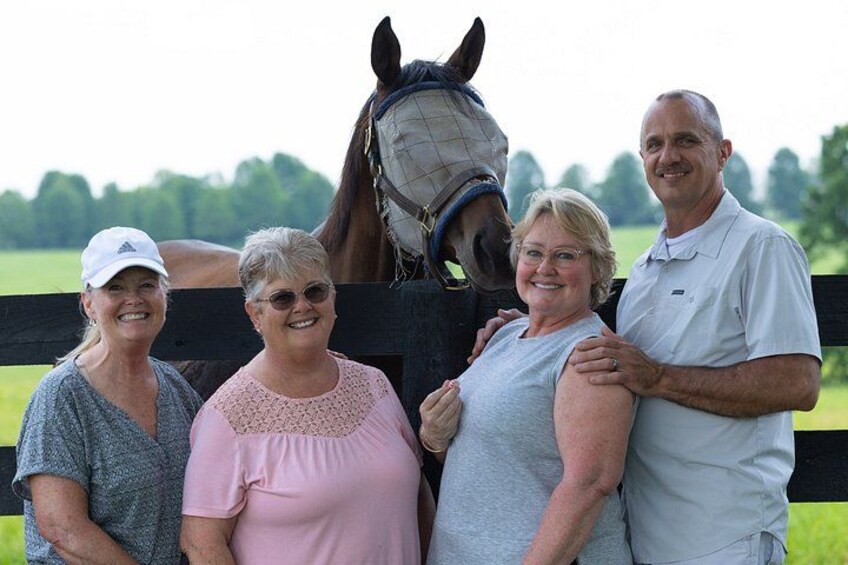 Four people standing in front of a horse with a black fence in the background. 5