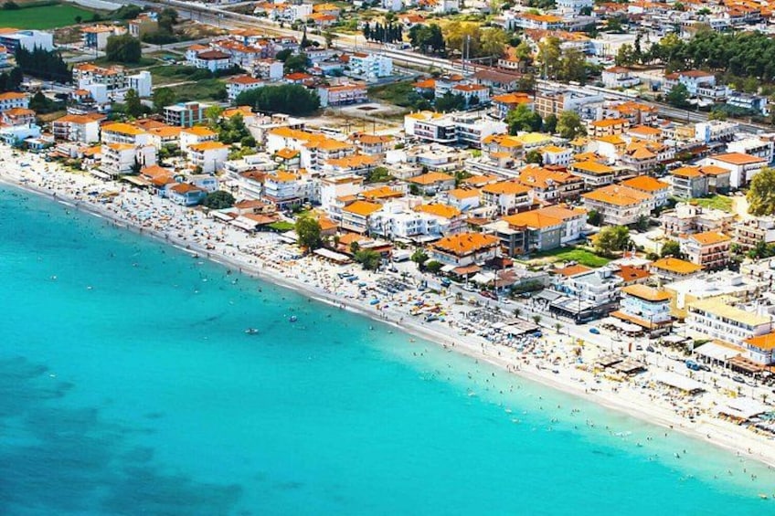 An aerial view of a coastal town with a beach, buildings, and a clear blue sea. 4