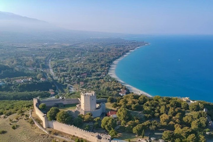 A coastal landscape with a castle, a beach, and a road. 2