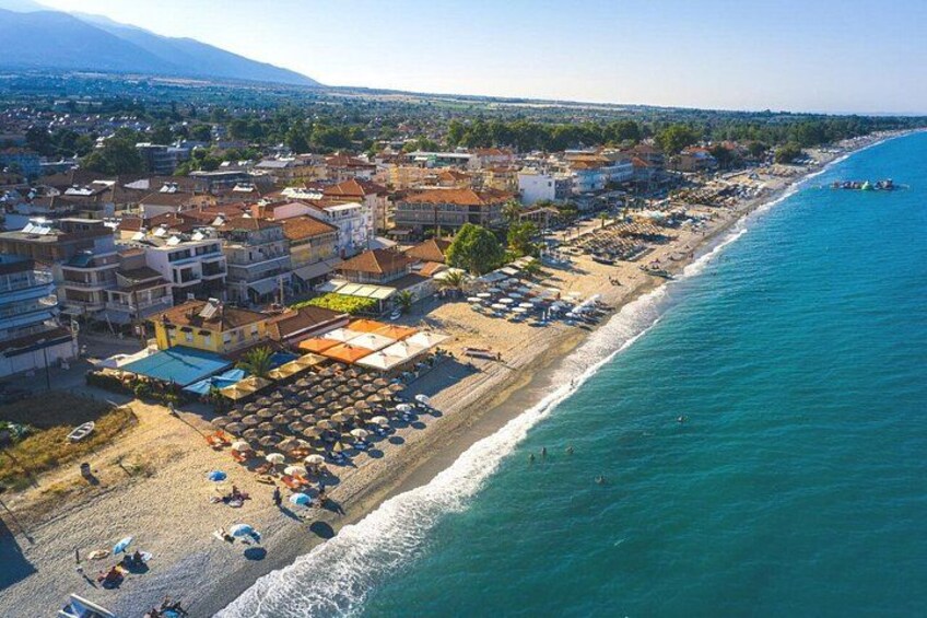 A coastal town with a beach, buildings, and a clear blue sea. 3