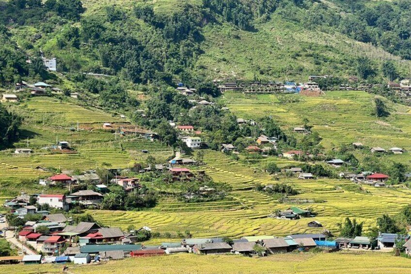 A rural landscape with terraced fields, scattered houses, and a hilly backdrop. 1