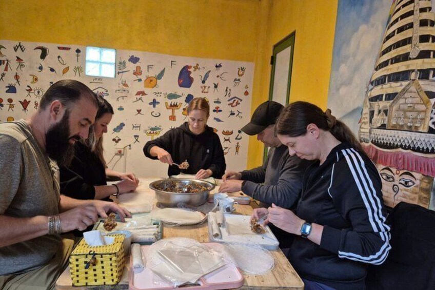 A group of people preparing food at a table with various ingredients and utensils. 5