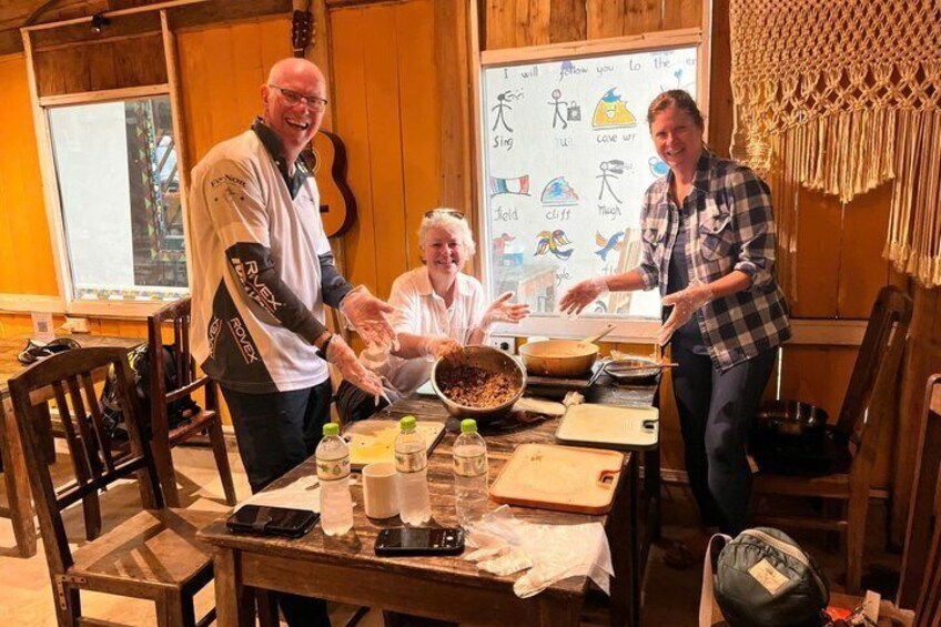 Three people at a wooden table with food, a whiteboard with drawings, and a guitar in the background. 4