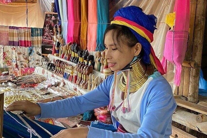 A person weaving at a market stall with colorful textiles and accessories. 4