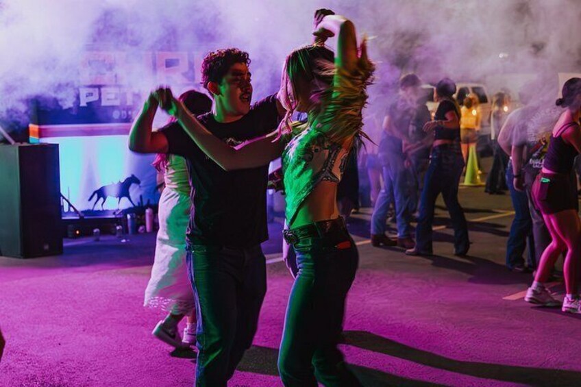People dancing in a crowded outdoor event with smoke effects. 2