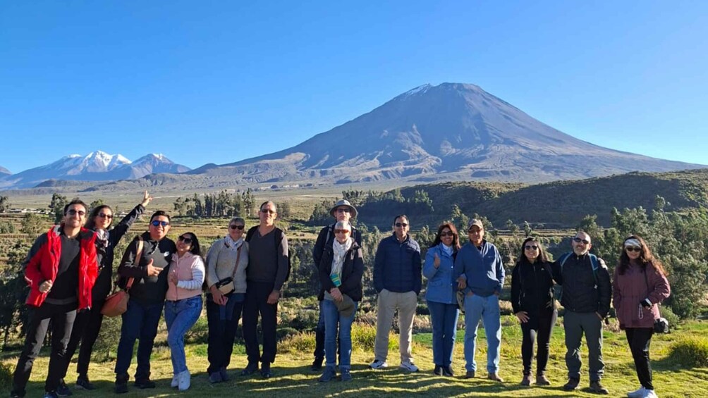 A group of people standing in a grassy field with a mountain in the background. 4