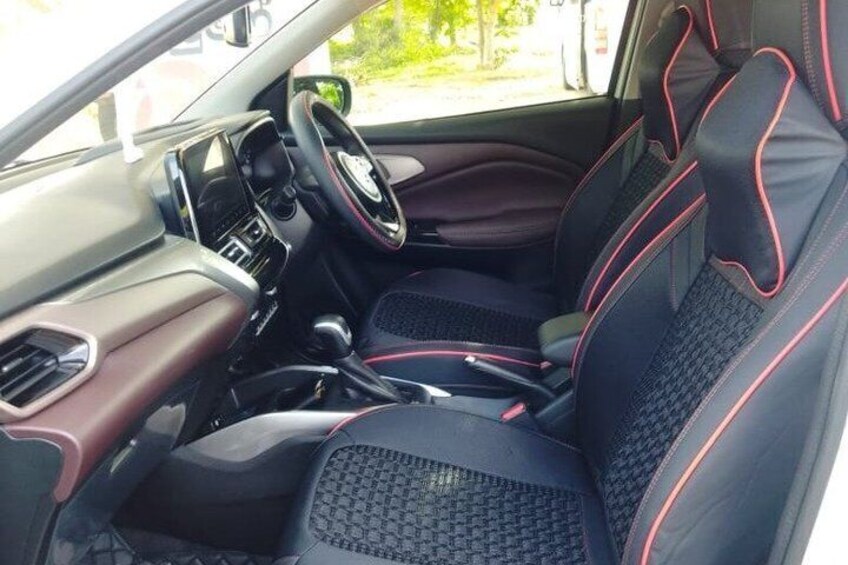 A car interior with black seats and red detailing, a steering wheel, and a dashboard. 2