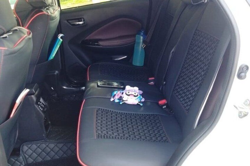 A car's interior with black seats, red stitching, and a small toy on the center console. 4