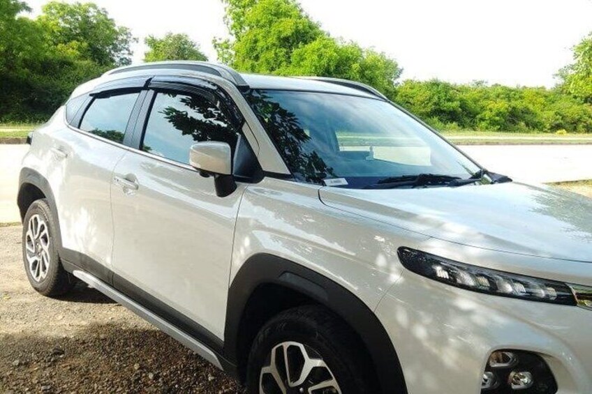 A silver SUV parked on a gravel surface with trees in the background. 5
