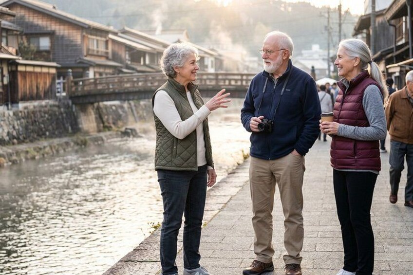 A riverside walkway with traditional buildings, a bridge, and people walking. 1