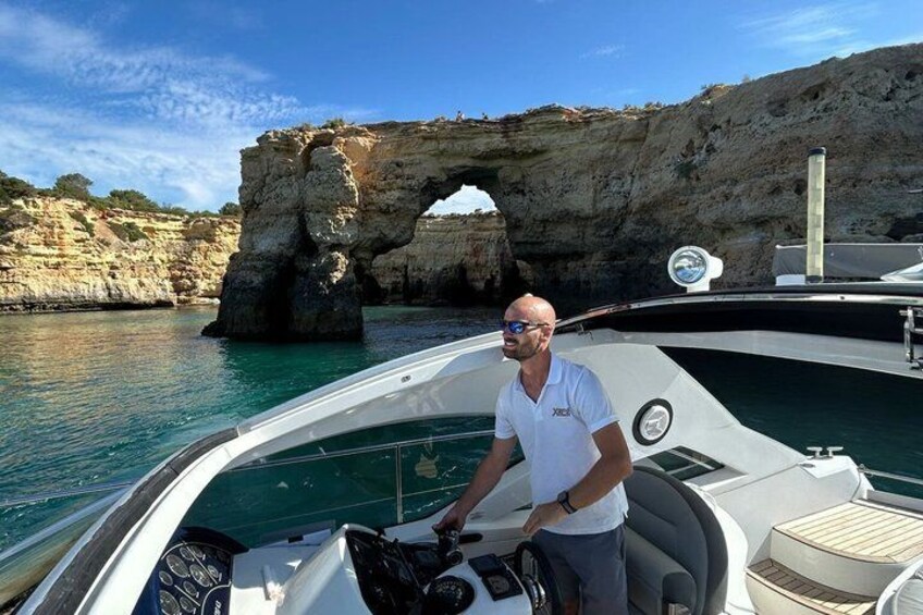A man on a boat near a rocky arch formation. 2