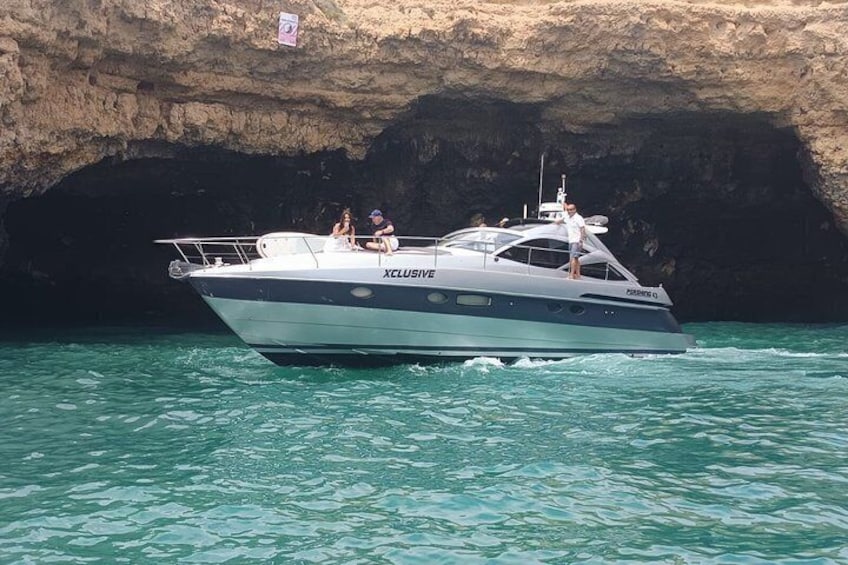 A yacht named 'Xclusive' anchored near a rocky cave. 3